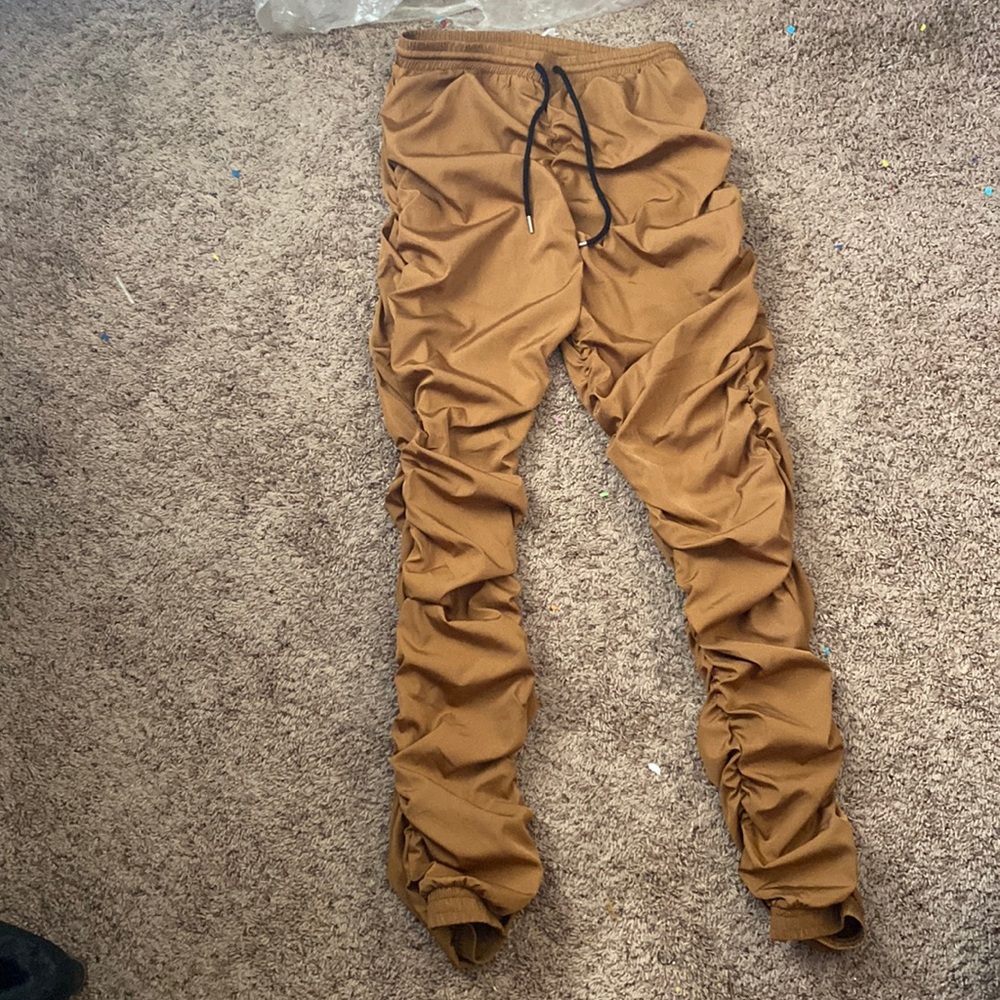 Stacked tan sweatpants with stitched seem on the butt line